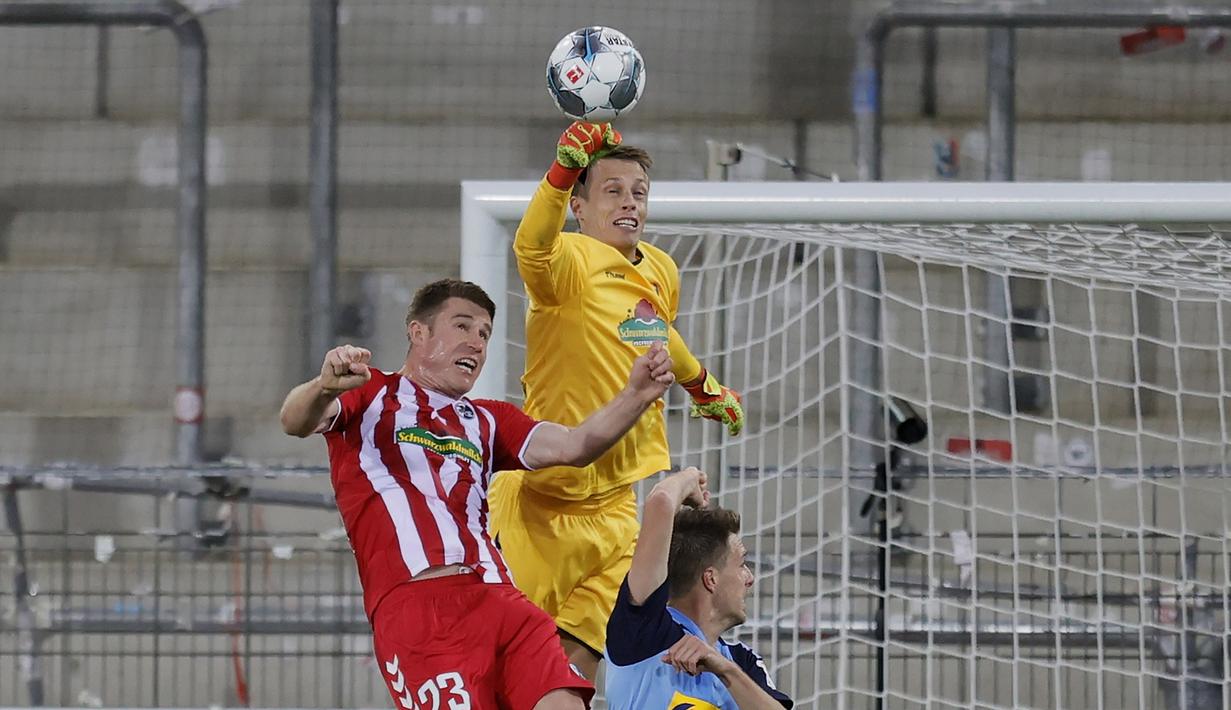 Kiper SC Freiburg, Alexander Schwolow, menepis bola saat melawan Borussia Monchengladbach pada laga lanjutan Bundesliga di Freiburg, Jumat (5/6/2020) waktu setempat. Monchengladbach kalah 0-1 atas Freiburg. (AFP/Ronald Wittek/Pool)