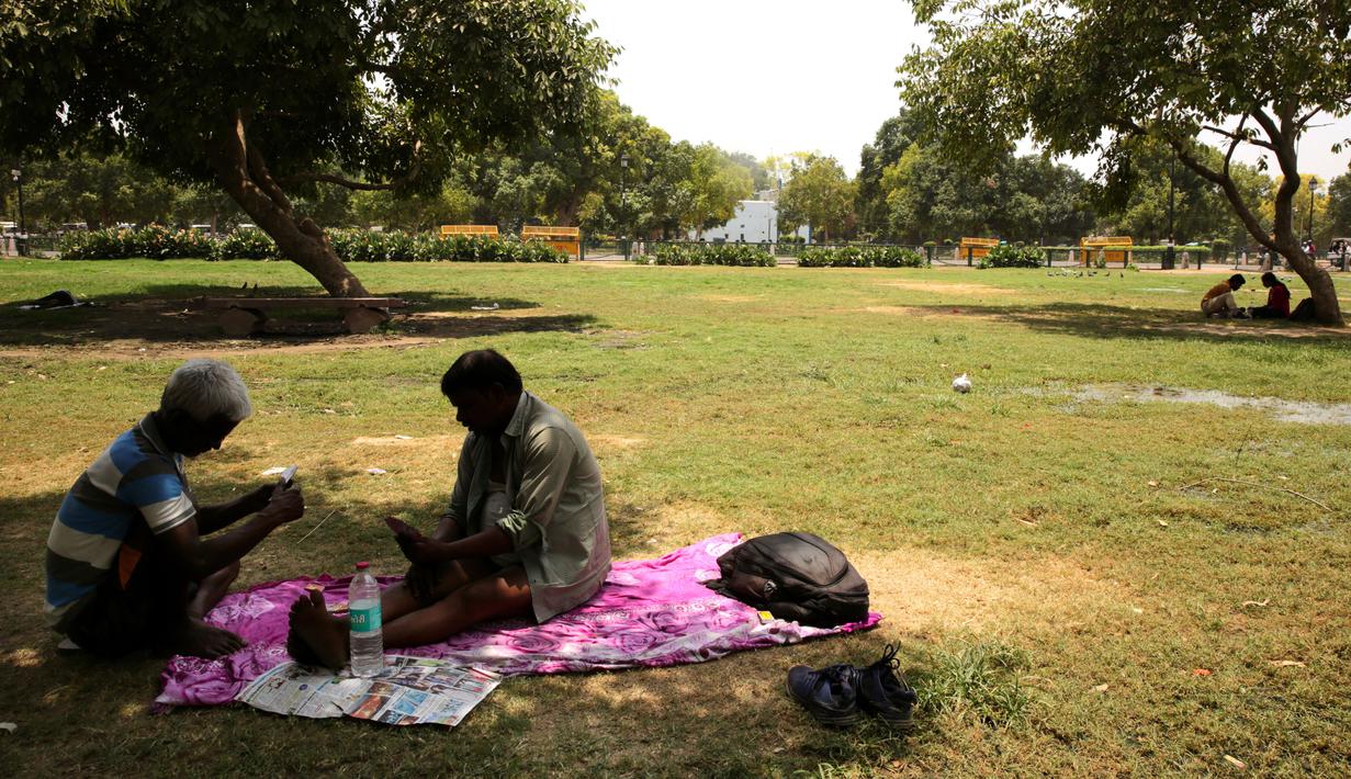Warga duduk di bawah pohon selama musim panas di New Delhi, India (10/6/2019). Kondisi gelombang panas yang parah menyapu bagian utara dan barat India dengan suhu maksimum melonjak hingga 48 derajat Celcius ( 118 F) di beberapa bagian Rajasthan. (AP Photo/Manish Swarup)