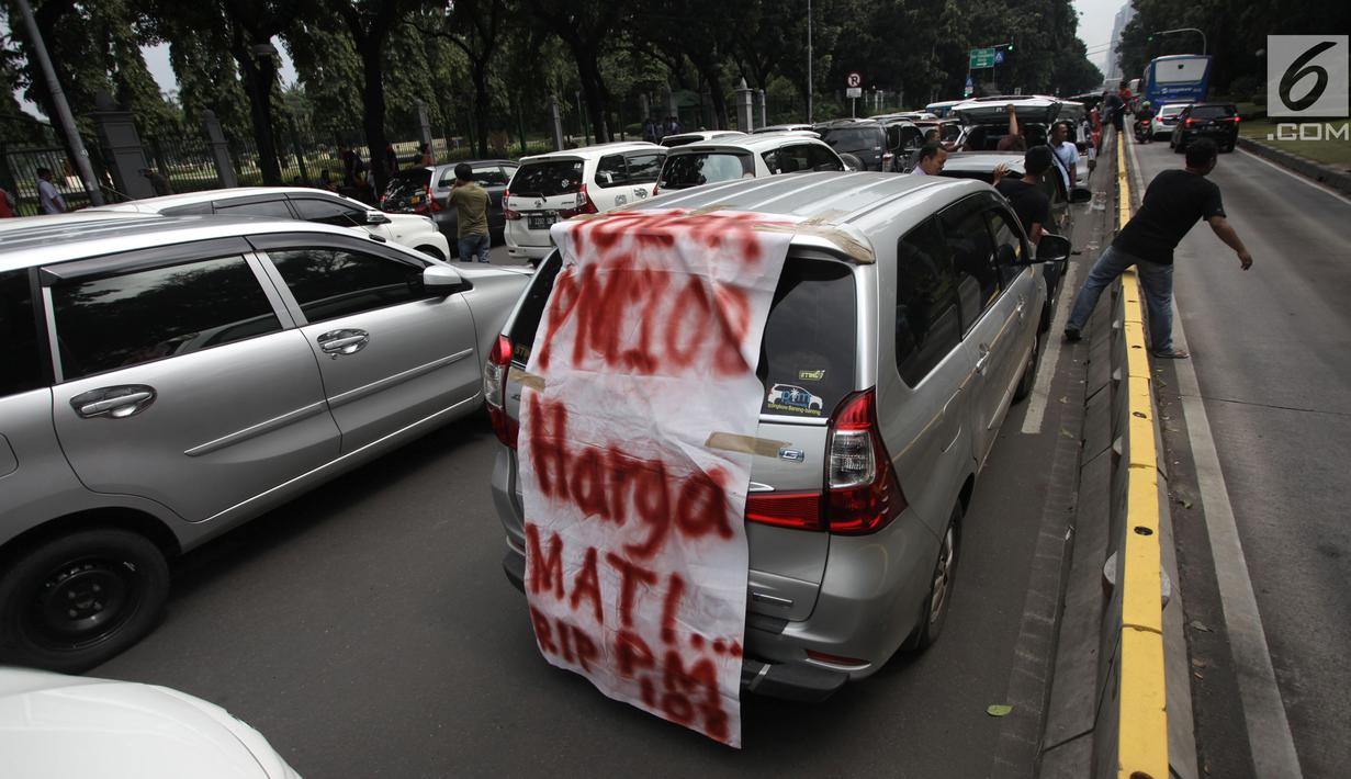 Sebuah spanduk terpampang saat ratusan sopir taksi online memarkir mobilnya di Jalan Medan Merdeka Barat, Jakarta, Rabu (14/2). Para pengemudi menolak Permenhub Nomor 108 karena dianggap memberatkan. (Liputan6.com/Arya Manggala)