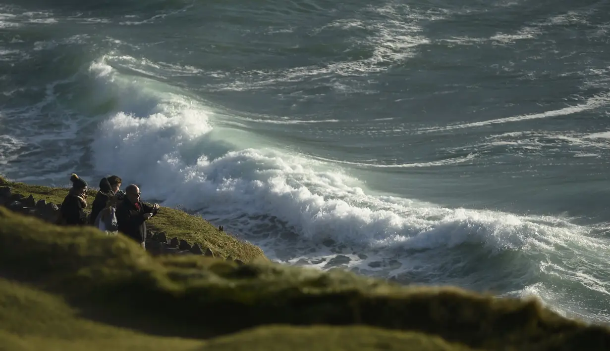 Pengunjung melihat deburan ombak di Slea Head, Ventry, Irlandia, Selasa (27/12). Irlandia mendapat julukan Pulau Zamrud karena memiliki pemandangan alam yang hijau terang. (REUTERS / Clodagh Kilcoyne)
