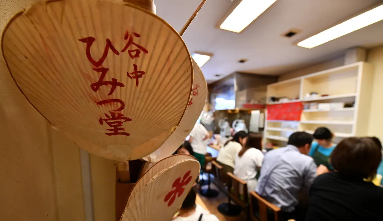 Pelanggan menikmati kakigori atau es serut di distrik Yanaka Tokyo, Jepang (21/6/2019). makanan penutup musim panas yang menyegarkan ini terbuat dari campuran es serut, sirup buah dan susu kental manis. (AFP Photo/Toshifumi Kitamura)