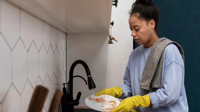 Seorang Wanita Sedang Mencuci Piring Kotor