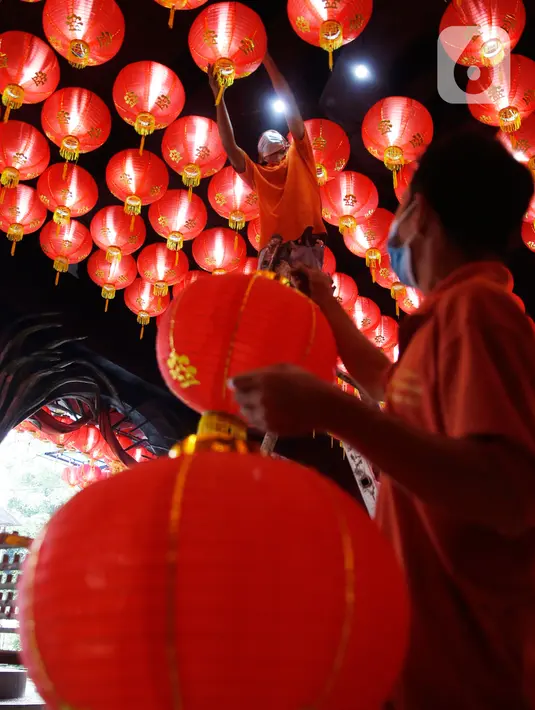 Pekerja dibantu rekannya memasang lampion pemberian umat di Klenteng Boen San Bio, Tangerang, Kamis (28/1/2021). Sebanyak 800  lampion dipasang untuk mempercantik Klenteng jelang perayaan Tahun Baru Imlek. (Liputan6.com/Angga Yuniar)