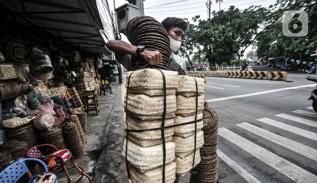 Pembeli membawa besek bambu di kawasan Jatinegara, Jakarta, Senin (19/7/2021). Pedagang mengaku harga jual besek bambu tetap stabil dengan kisaran Rp3.000 hingga Rp5.000 per buah. (merdeka.com/Iqbal S. Nugroho)