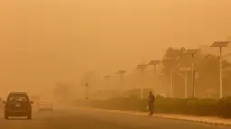 Seorang pria terlihat saat sepanjang jalan raya yang diselimuti debu tebal selama terjangan badai pasir di Kuwait City, Kuwait, pada 17 Juni 2021. Terjangan badai pasir ini membuat jarak pandang atau visibilitas di beberapa daerah turun hingga kurang dari 100 meter. (AFP/YasserAl-Zayyat)
