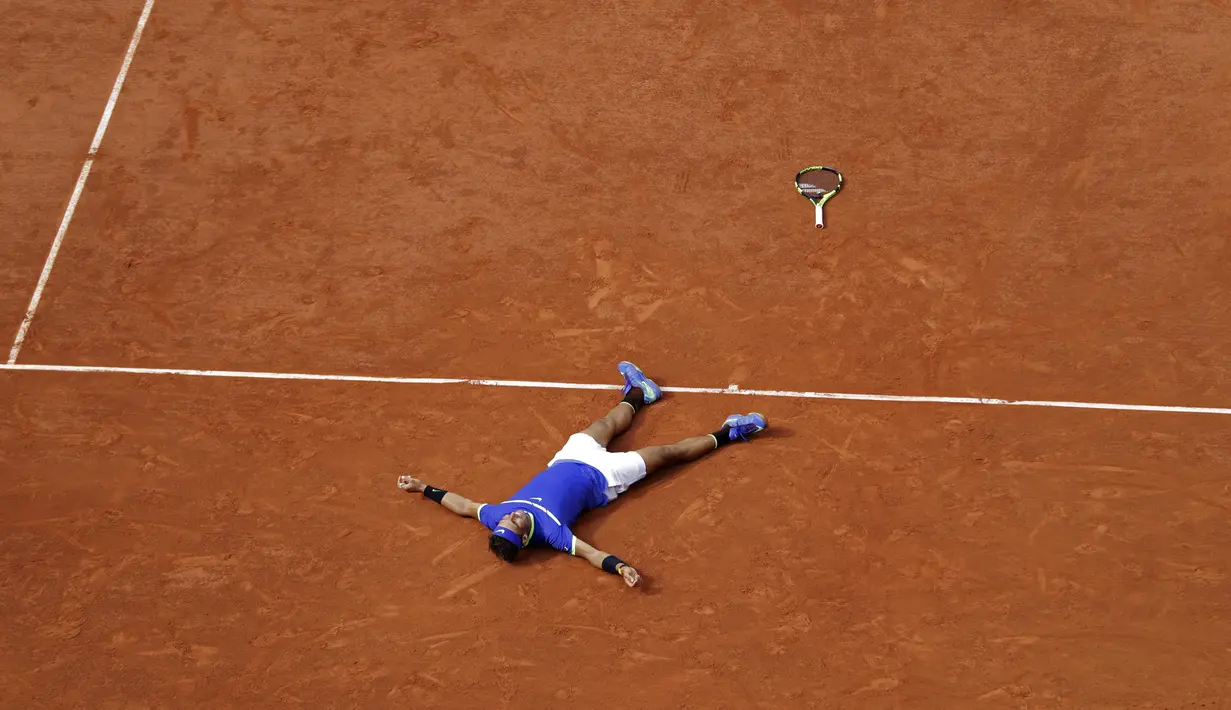 Rafael Nadal merayakan kemenangan dengan tidur diatas lapangan pada laga Final Tunggal Putra, Prancis Terbuka 2017 di Roland Garros stadium, Paris, (11/6/2017). Nadal menang  6-2, 6-3, 6-1. (AP/Petr David Josek)