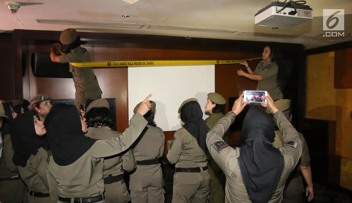 Petugas Satpol PP wanita memasang garis polisi Pamong Praja di Sense Karaoke di Mangga Dua Square, Jakarta, Kamis (19/4). Sense Karaoke ditutup total usai ditemukan peredaran narkoba. (Liputan6.com/Arya Manggala)