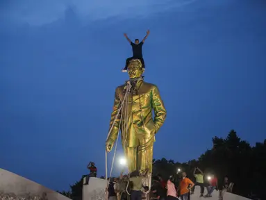 Pengunjuk rasa anti-pemerintah naik ke atas patung Sheikh Mujibur Rahman, bapak pendiri Bangladesh dan orang tua dari Perdana Menteri terguling Sheikh Hasina, di Dhaka, Senin (5/8/2024). (Abu SUFIAN JEWEL / AFP)