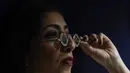 Seorang anggota staf mengenakan kacamata Mughal dengan lensa berlian, dalam bingkai berlian, di Sotheby's, di London, Jumat (22/10/2021). Kacamata adalah contoh yang sangat langka dari kerajinan perhiasan Mughal. (AP Photo/Alberto Pezzali)
