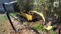 Petugas menggunakan alat berat backhoe membersihan jalan dari longsoran tanah di RT 04/RW 03, Kademangan, Keranggan, Setu, Tangerang Selatan, Banten, Selasa (3/12/2019). Longsor pada Senin sore kemarin menewaskan seorang pengendara sepeda motor yang melintas, Anggi (23). (merdeka.com/Arie Basuki)