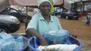 Seorang perempuan menjual makanan di sebuah jalan di Conakry, Guinea, Rabu (8/9/2021). Militer Guinea melakukan kudeta dan membubarkan pemerintahan serta konstitusi negara di Afrika Barat itu pada Minggu, 5 September lalu. (AP Photo/Minggu Alamba)