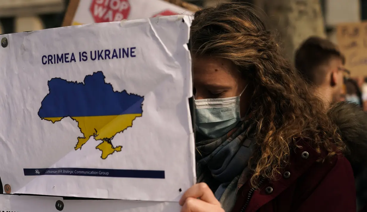 Seorang demonstran Pro-Ukraina memegang poster saat demonstrasi di luar Downing Street, di London, Kamis (24/2/2022). Demonstran turun ke jalan di London, Tokyo, Paris dan banyak kota lain untuk memprotes invasi Rusia ke Ukraina. (AP Photo/Alberto Pezzali)