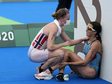 Atlet Belgia Claire Michel dibantu oleh atlet Norwegia Lotte Miller setelah menyelesaikan kompetisi triathlon individu putri Olimpiade Tokyo 2020 di Tokyo, Jepang, 27 Juli 2021. (AP Photo/David Goldman)