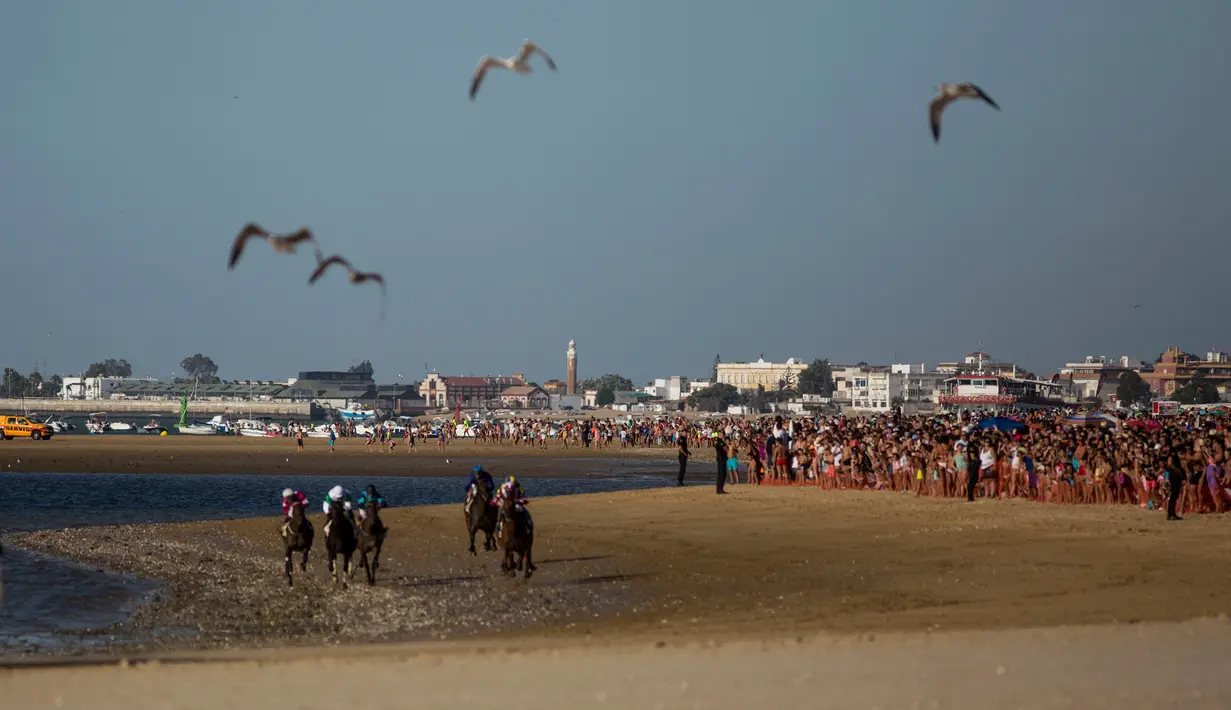 Penonton menyaksikan lomba pacuan kuda di tepi pantai di Sanlucar de Barrameda, Spanyol pada 11 Agustus 2019. Balap kuda di tepi pantai ini merupakan acara tahunan yang telag berlangsung selama lebih dari 140 tahun. (AP Photo/Javier Fergo)