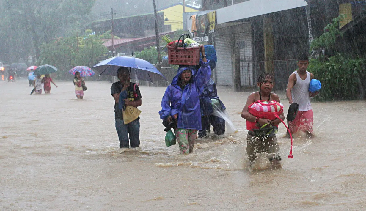Sejumlah warga menyeberangi jalan yang terendam banjir usai badai tropis Linfa melanda wilayah San Fernando, La Union, Filipina, Senin (6/7/2015). Badai tropis Linfa yang memiliki kecepatan 100 km per jam itu sedang bergerak ke utara. (REUTERS/TJ Corpuz)