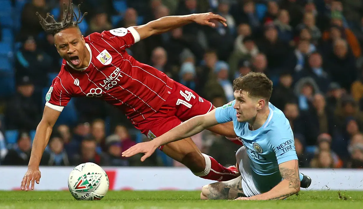 Pemain Manchester City, John Stones berebut bola dengan pemain Bristol City, Bobby Reid pada leg pertama semifinal Piala Liga Inggris di Stadion Etihad, Selasa (9/1). Manchester City harus bersusah payah Bristol City 2-1. (AP/Dave Thompson)
