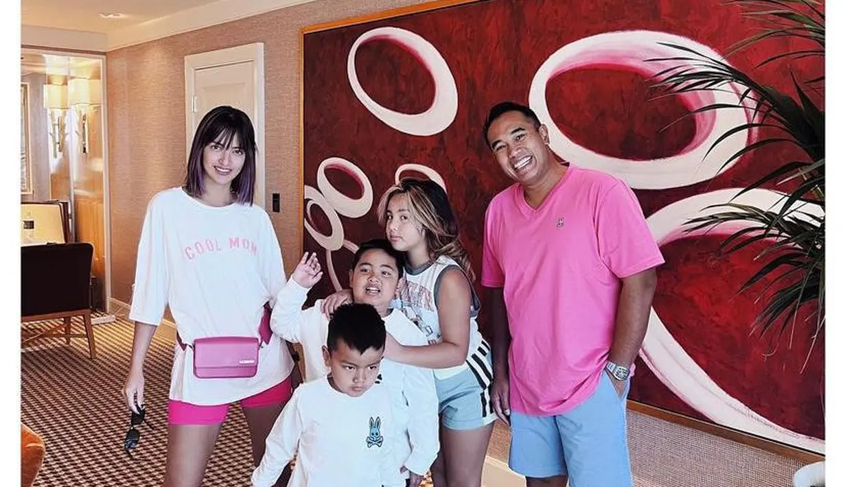Tampil kompak bareng keluarga dengan outfit nuansa pink, Nia Ramadhani tampak mengenakan white t-shirt, hot pants pink, dan waist bag. (Instagram/ramadhaniabakrie).
