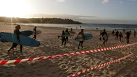 Sejumlah peselancar memenuhi pantai  Bondi di Sydney, Selasa, (28/4/2020). Otoritas setempat mengatakan hanya akan membuka dua pintu yang dapat diakses wisatawan. Walikota Waverley Paula Masseols mengimbau agar warga di luar Bondi tidak mengunjungi pantai tersebut. (AP Photo/Rick Rycroft)