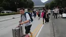 Penumpang berjalan kaki ke bandara ketika pemrotes pro-demokrasi memblokir jalan di luar bandara di Hong Kong (1/9/2019). Demonstran pro-demokrasi penentang RUU Ekstradisi kembali menjadikan bandara sebagai tempat aksi demo. (AP Photo/Kin Cheung)