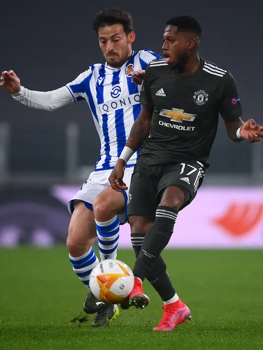 Gelandang Real Sociedad, Mikel Merino berusaha merebut bola dari gelandang Manchester United, Fred pada pertandingan leg pertama babak 32 besar Liga Europa di stadion Juventus, Turin (19/2/2021). MU menang telak atas Sociedad 4-0.  (AFP/Marco Bertorello)