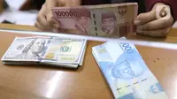 Petugas menunjukkan mata uang rupiah dan dolar di Jakarta, Senin (9/11/2020). Menjelang siang, rupiah terus menguat ke level 14.145 per dolar AS. (Liputan6.com/Angga Yuniar)