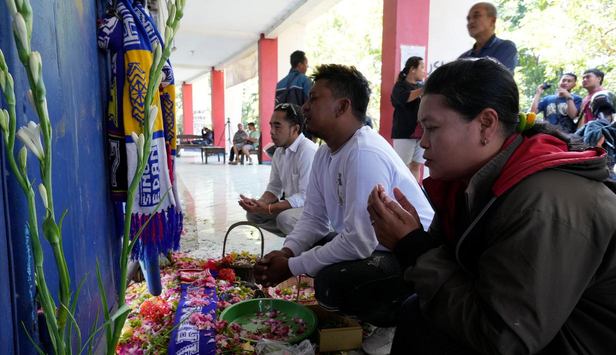 Orang-orang berkumpul untuk berdoa bagi para korban kerusuhan di depan Gerbang 13, Stadion Kanjuruhan, Malang, Selasa (4/10/2022). Polri menjatuhkan sanksi kepada 10 anggota polisi dan menyelidiki 18 orang lainnya buntut tragedi kerusuhan yang menewaskan 125 orang di Stadion Kanjuruhan. (AP Photo/Achmad Ibrahim)