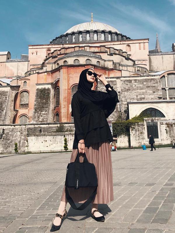 Citra Kirana yang mantan finalis Gadis Sampul 2007 ini tampak modis dengan hijab dan atasan berwarna hitam dipadu dengan rok panjang berwarna krem saat berpose di Hagia Sophia, Turki. (Liputan6.com/IG/@citraciki)
