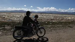 Pengendara sepeda motor melewati sampah di tepian Danau Uru Uru dekat Oruro, Bolivia, Kamis (25/3/2021).  Mayoritas sampah rumah tangga ini terbawa dari aliran sungai yang bermuara di danau ini. (AP Photo / Juan Karita)