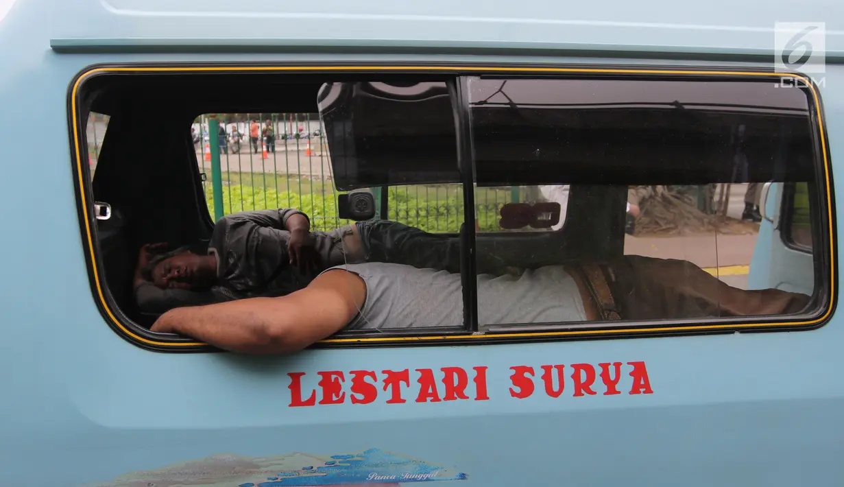 Seorang sopir angkot M08 trayek Tanah Abang-Kota tertidur di dalam kendaraannya di Jalan Jatibaru, Jakarta, Kamis (22/2). Para sopir terlihat sedang menunggu rekan sopir M03 dan M10 yang juga akan ikut berunjuk rasa. (Liputan6.com/Arya Manggala)