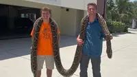 Stephen Gauta (kiri) dan Jake Waleri membawa ular piton sepanjang 19 kaki ke Konservasi Florida Barat Daya di Naples, Fla., untuk diukur dan disumbangkan untuk penelitian. (Dok: Konservasi Florida Barat Daya)