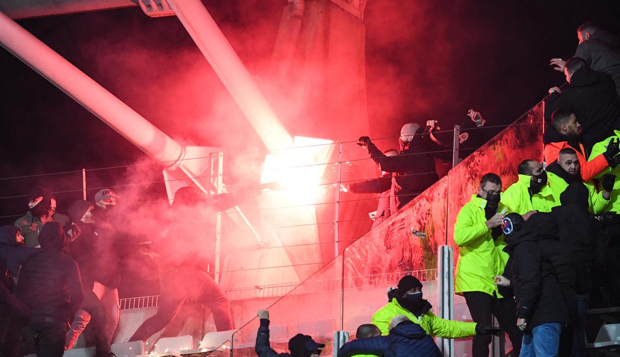 Suporter memegang suar pada pertandingan 64 besar Piala Prancis antara Paris FC dan Olympique Lyon di stadion Charlety, Paris, Jumat (17/12/2021). Pendukung saling bertarung dan beberapa dari mereka turun ke lapangan dan melemparkan suar di babak pertama yang berakhir imbang 1-1. (Bertrand GUAY/AFP)
