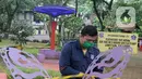 Petugas Dinas Lingkungan Hidup dan Kebersihan (DLHK) Kota Depok memasang garis larangan melintas umum di Taman Merak, Limo, Depok, Senin (25/1/2021). Pembatasan dan penutupan taman tersebut dilakukan dalam rangka Pemberlakuan Pembatasan Kegiatan Masyarakat (PPKM). (merdeka.com/Arie Basuki)