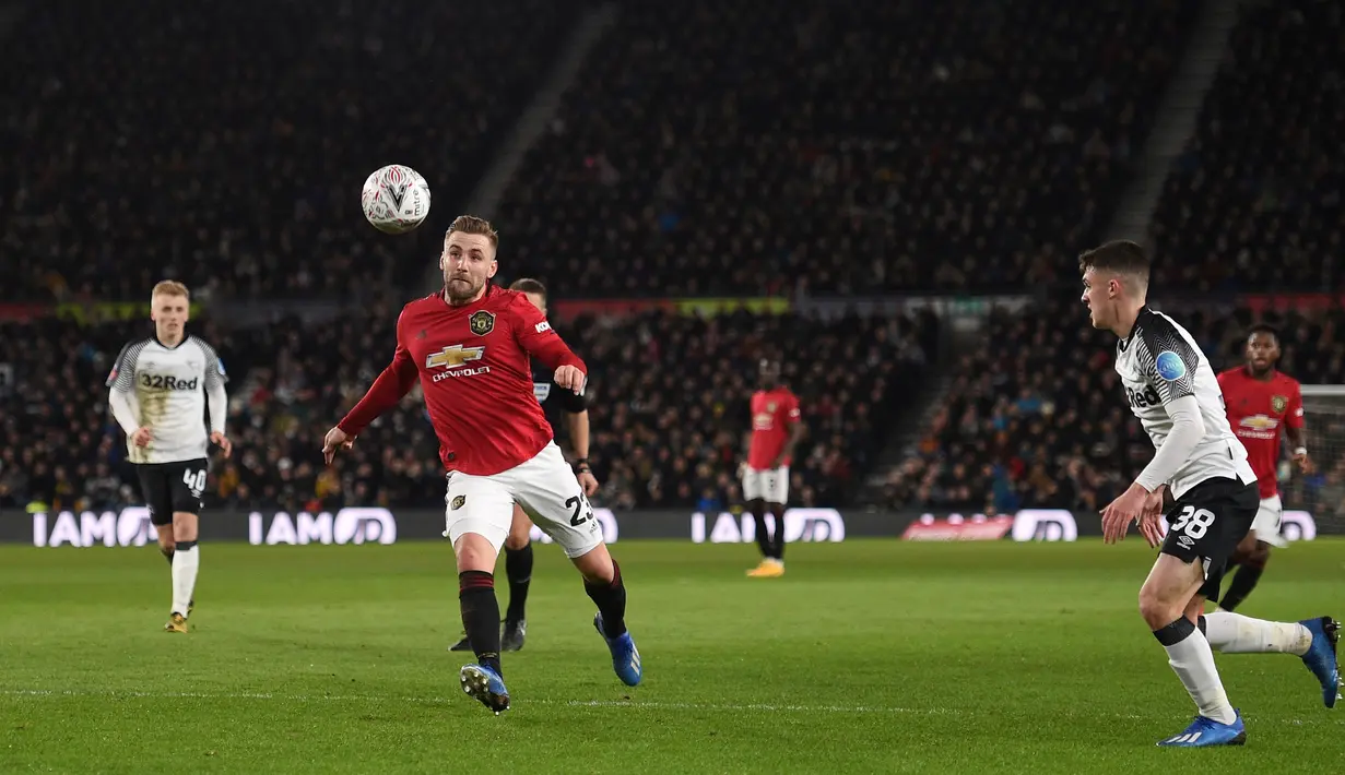Bek Manchester United, Luke Shaw, berebut bola dengan pemain Derby Country pada laga babak kelima Piala FA di Pride Park Stadium, Kamis (5/3). Manchester United menang 3-0 atas Derby Country. (AFP/Oli Scarff)