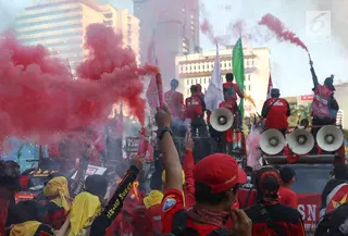 Sejumlah buruh menyalakan bom asap saat menutup aksi Hari Buruh Internasional di Jalan Medan Merdeka Barat, Jakarta, Rabu (5/1/2019). Aksi May Day 2019 di Jakarta ditutup oleh buruh dengan menyalakan kembang api sebagai simbol berjalannya demo dengan damai. (Liputan6.com/Helmi Fithriansyah)