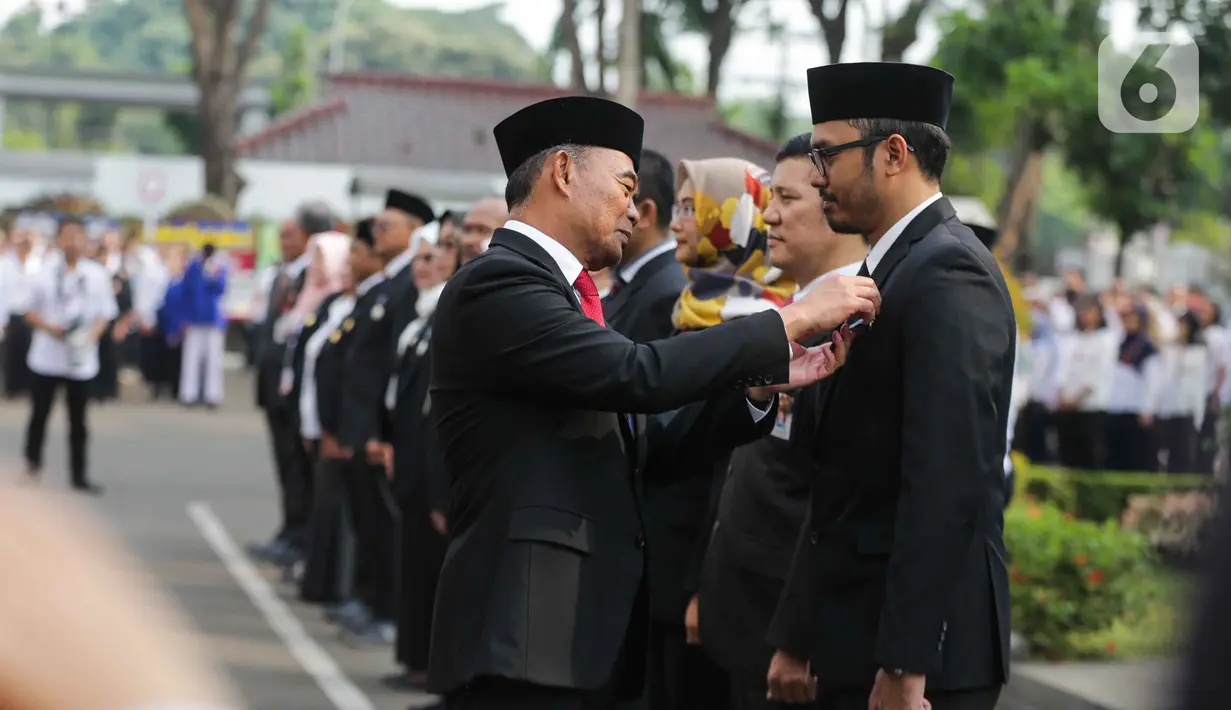 Menko PMK Muhadjir Effendy menyematkan tanda kehormatan Bintang Satyalancana Karya Satya kepada sejumlah PNS saat memimpin upacara peringatan Sumpah Pemuda di kantor Kemenko PMK, Jakarta, Senin (28/10/2019). (Liputan6.com/Faizal Fanani)