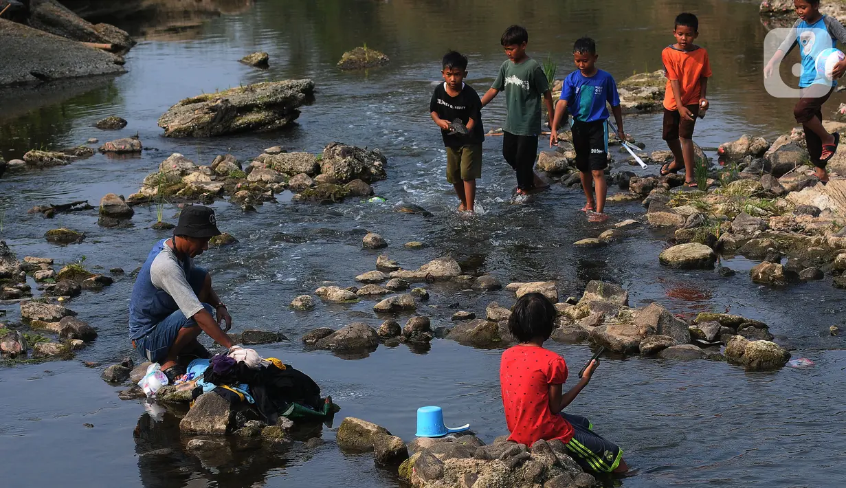 Warga mencuci pakaian pada aliran di pintu air Bendungan Cibeet, Wanajaya, Telukjambe, Karawang, Jawa Barat, Sabtu (7/10/2023). (merdeka.com/Imam Buhori)