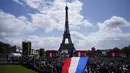 <p>Seorang pria mengibarkan bendera Prancis di zona penggemar Olimpiade di Trocadero Gardens di depan Menara Eiffel di Paris, Minggu (8/8/2021). Pelepasan tongkat tuan rumah akan dibagi antara Stadion Olimpiade di Tokyo dan pesta publik dan konser di Paris. (AP Photo/Francois Mori)</p>