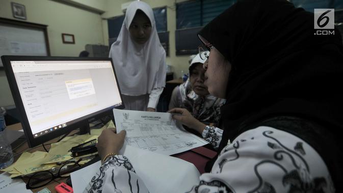 Panitia pelaksana saat membantu salah satu pendaftar dalam proses pengambilan nomor token PPDB di SMPN 92, Jakarta, Senin (25/6). (Merdeka.com/Iqbal S Nugroho)
