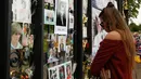 Seorang turis wanita mengamati memorabilia Putri Diana yang diletakkan di luar Istana Kensington, London, Selasa (29/8). Bunga, foto hingga lilin diletakkan di luar Istana untuk mengenang 20 tahun kematian Putri Diana. (AP Photo/Alastair Grant)