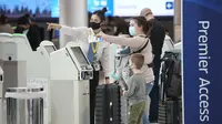 Agen United Airlines mengarahkan pengunjing setelah mereka mendaftar masuk di loket terminal Bandara Internasional Denver AS (26/12/2021). Maskapai menunda ratusan penerbangan pada Minggu (26/12). (AP Photo/David Zalubowski)