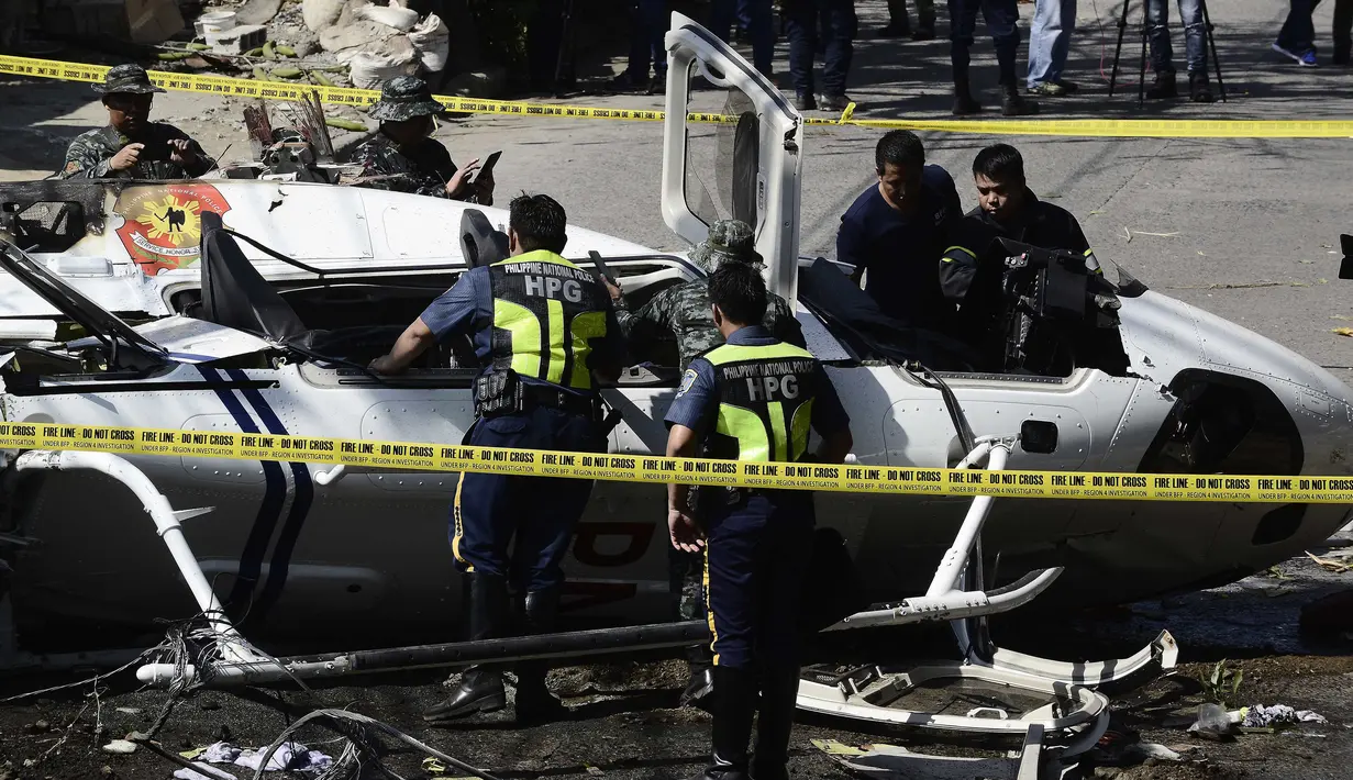 Penyelidik berdiri di dekat puing-puing Helikopter bell 429 yang jatuh di Kota San Pedro, selatan Manila, Kamis (5/3/2020). Helikopter yang membawa Kepala Polisi Filipina Jenderal Archie Francisco Gamboa dan beberapa pejabat PNP lainnya itu jatuh tidak lama setelah lepas landas. (DANTE PERALTA/AFP)
