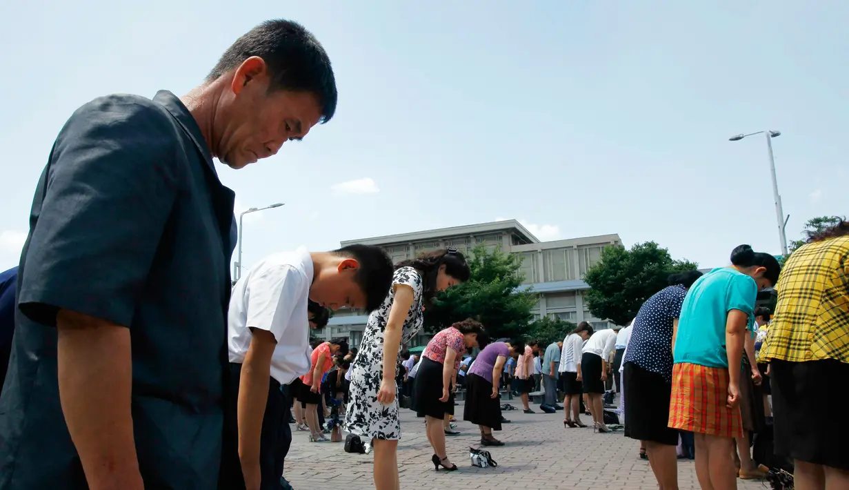 Para pekerja membungkukkan badan mereka saat memberi penghormatan selama tiga menit dalam peringatan 25 tahun meniggalnya pemimpin Kim Il Sung di Pyongyang, Korea Utara, Senin(8/7/2019). (AP Photo/Cha Song Ho)