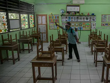 Seorang guru mendisinfeksi kelas yang akan digunakan di SDN Kenari 08, Jakarta, Selasa (6/4/2021). Pemerintah Provinsi DKI Jakarta akan melakukan uji coba pembelajaran tatap muka terbatas di 100 sekolah mulai 7 April hingga 29 April 2021. (Liputan6.com/Faizal Fanani)