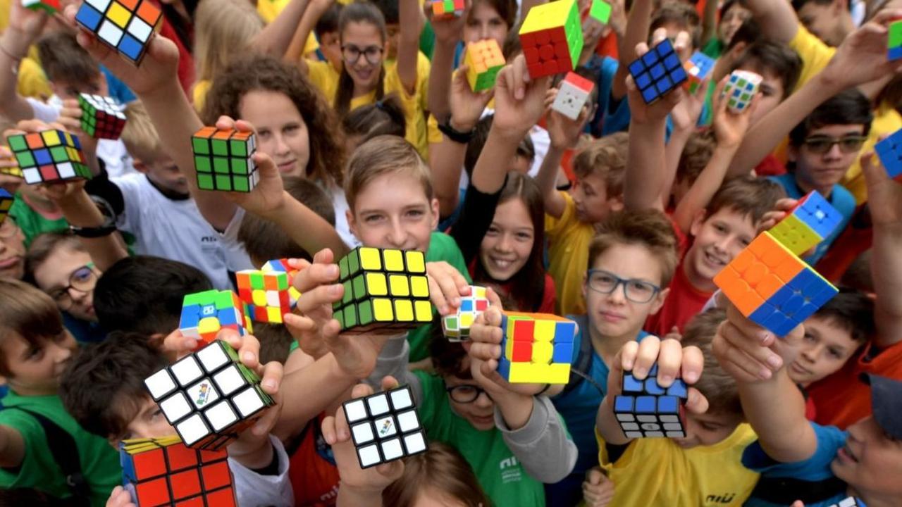 Acara ini diwarnai dengan flashmob spektakuler yang melibatkan ratusan murid dari berbagai sekolah di seluruh negeri. Mereka masing-masing memegang Kubus Rubik berwarna-warni. Foto: Ferenc ISZA / AFP<br>