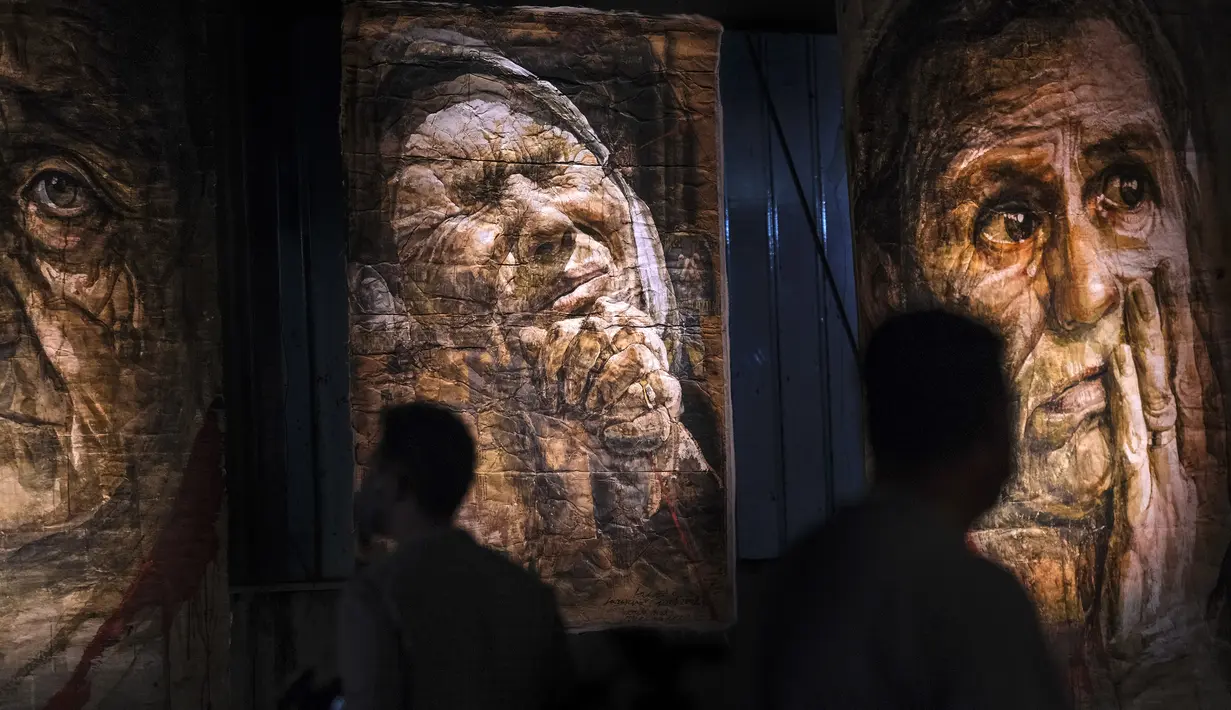 Sejumlah pengunjung menghadiri pameran seni karya pelukis Safet Zec di Potocari, Bosnia, Selasa (7/7/2020). Pameran tersebut didedikasikan untuk lebih dari 8.000 korban tewas dalam 10 hari pembantaian setelah Srebrenica dikuasai oleh pasukan Serbia pada 11 Juli 1995. (AP Photo/Kemal Softic)