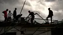 Sejumlah warga membersihkan puing-puing di sebuah bangunan setelah badai tornado menghantam Regla, Kuba (28/1). Hantaman tornado juga merobohkan tiang-tiang listrik di daerah tersebut. (AP Photo/Ramon Espinosa)