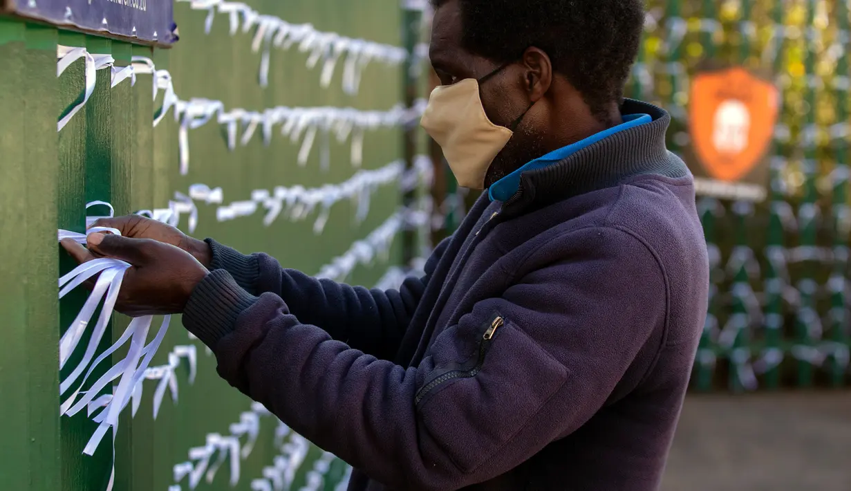 Leonard Makuya, seorang pengurus, mengikat pita ke pagar gereja St James Presbyterian di Bedford Gardens, Johannesburg, Rabu (29/7/2020). Pita tersebut mewakili warga Afrika Selatan yang meninggal akibat virus corona COVID-19. (AP Photo/Themba Hadebe)