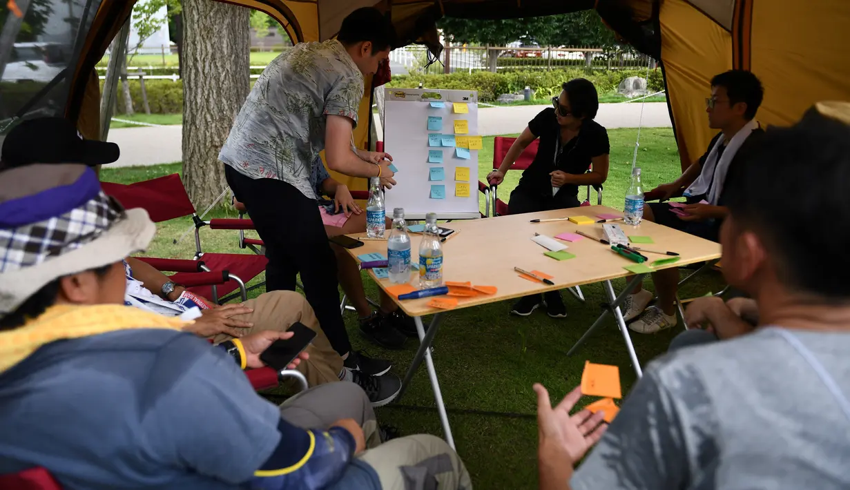 Foto 11 September 2018, karyawan perusahaan bekerja di dalam tenda kemah di halaman luar gedung kantor di Tokyo, Jepang. Di tempat ini, tenda-tenda kemah para pekerja berdiri di antara gedung-gedung tinggi yang menjulang. (Toshifumi KITAMURA/AFP)