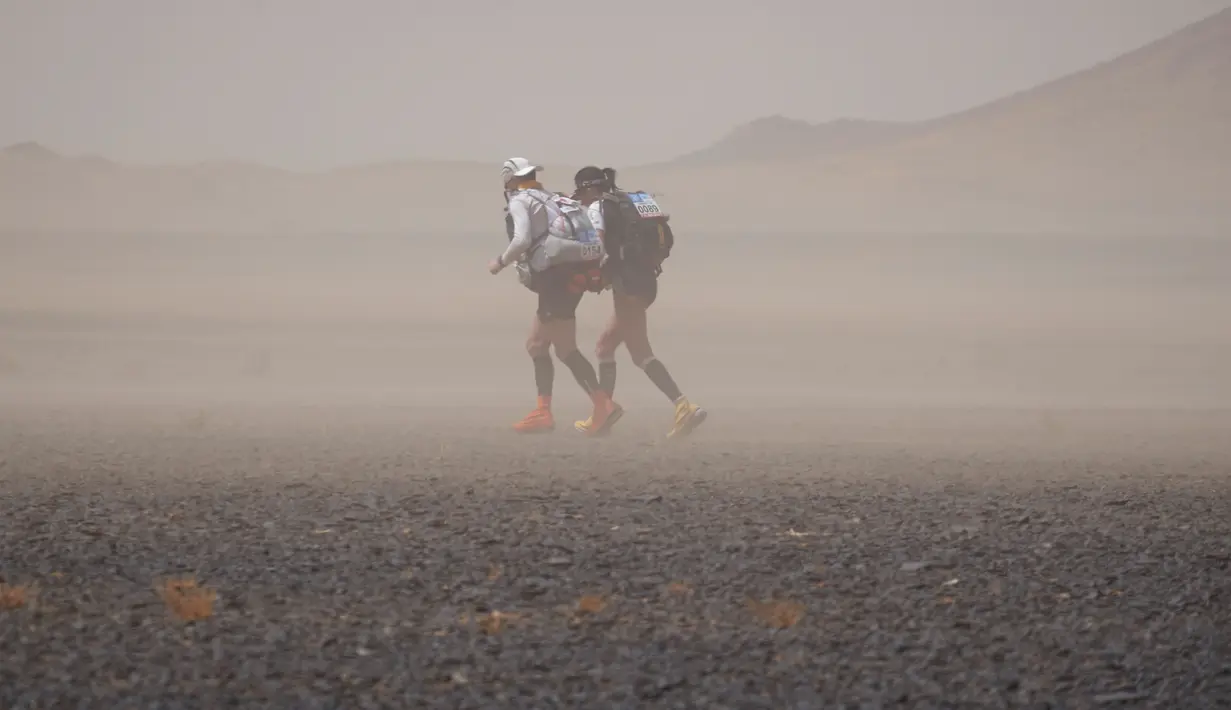 Perjuangan dua peserta melintasi gurun Sahara dalam kejuaraan marathon des Sables di Maroko Selatan, (10/4). Marathon des Sables kali ini merupakan gelaran yang ke-31. (AFP PHOTO/JEAN-PHILIPPE Ksiazek)