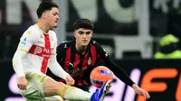 Penyerang Portugal Genoa #09, Vitinha, berebut bola dengan bek AC Milan Italia #33, Davide Bartesaghi (kanan), selama pertandingan Serie A Italia antara AC Milan dan Genoa di stadion San Siro di Milan, Italia utara, Jumat (9-1-2026) dini hari WIB. (Stefano RELLANDINI/AFP)